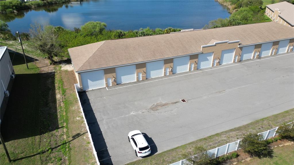 An aerial view shows a long storage building with multiple garage doors beside a lake — 3921 TAYLOR ROAD UNIT A1, PUNTA GORDA, FL