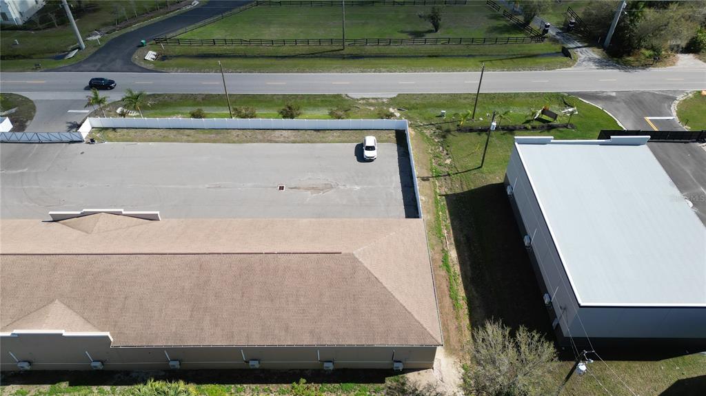 An aerial view shows two commercial buildings separated by a paved lot and white fencing — 3921 TAYLOR ROAD UNIT A1, PUNTA GORDA, FL