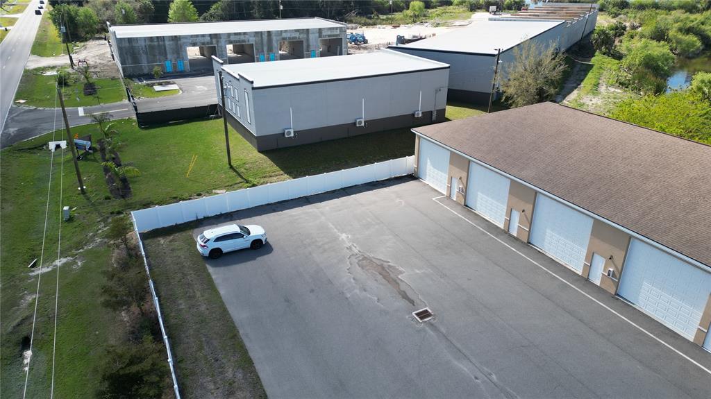 An aerial view shows a commercial building with a parking lot and a white fence — 3921 TAYLOR ROAD UNIT A1, PUNTA GORDA, FL