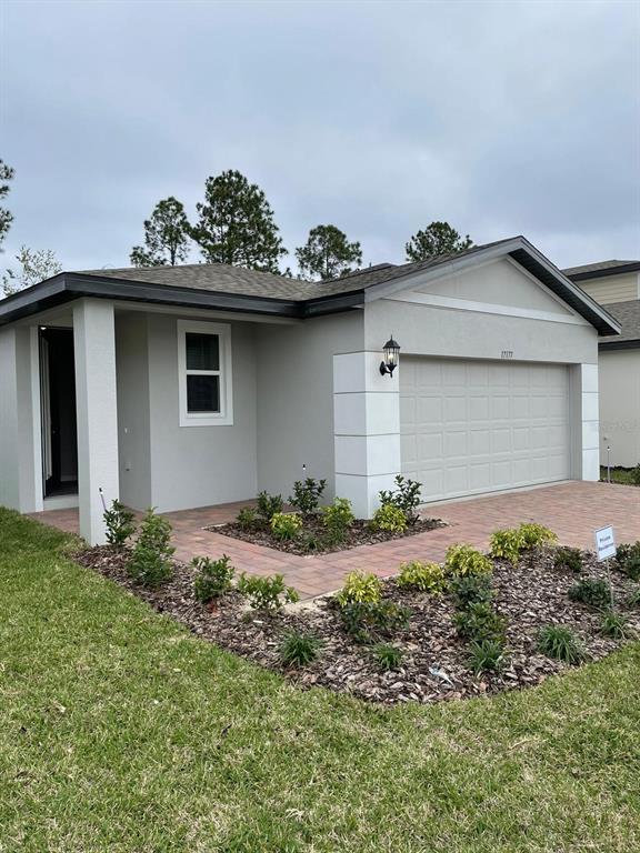 A single-story house with a gray stucco exterior, a two-car garage, and a paved walkway — 17177 CAGAN CROSSINGS BOULEVARD, CLERMONT, FL