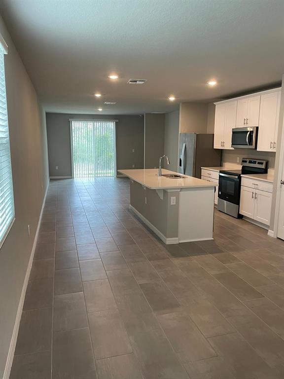 A kitchen with white cabinets and a center island opens into a spacious living area — 17177 CAGAN CROSSINGS BOULEVARD, CLERMONT, FL
