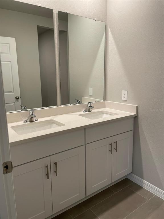 A bathroom features a double-sink vanity with white cabinets, a light countertop, and two mirrors — 17177 CAGAN CROSSINGS BOULEVARD, CLERMONT, FL