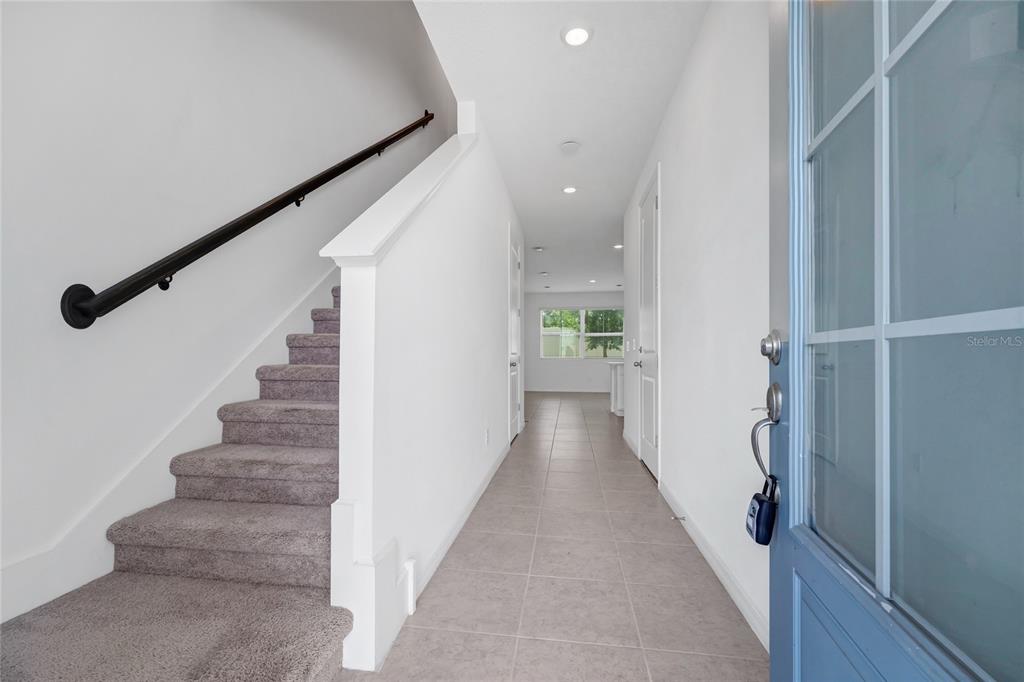 An entryway features a carpeted staircase with a handrail, tiled flooring, and a blue door — 763 LONGBOAT DRIVE, DAVENPORT, FL