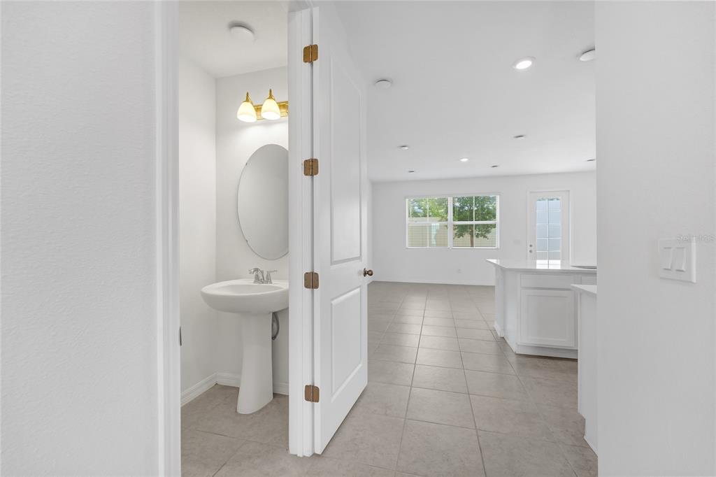 A view from a doorway into a half bathroom and an adjacent open-concept kitchen area — 763 LONGBOAT DRIVE, DAVENPORT, FL