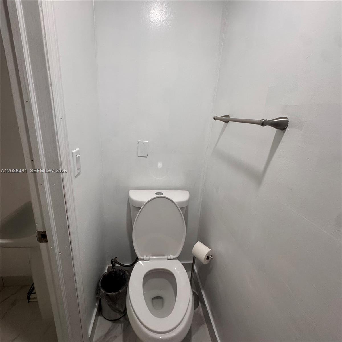 A small bathroom features a white toilet, a towel bar, and a toilet paper holder — MIAMI, FL