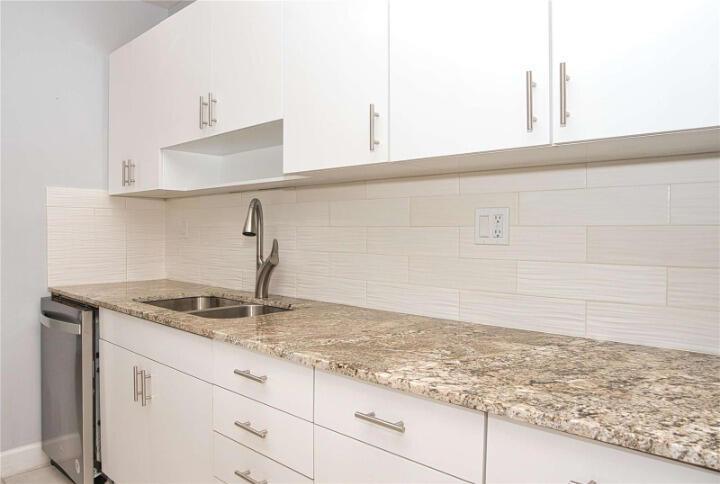 A kitchen features white cabinets, granite countertops, a stainless steel sink, and a tiled backsplash — 19355 Turnberry Way # 3d, Miami FL 33180, MIAMI, FL