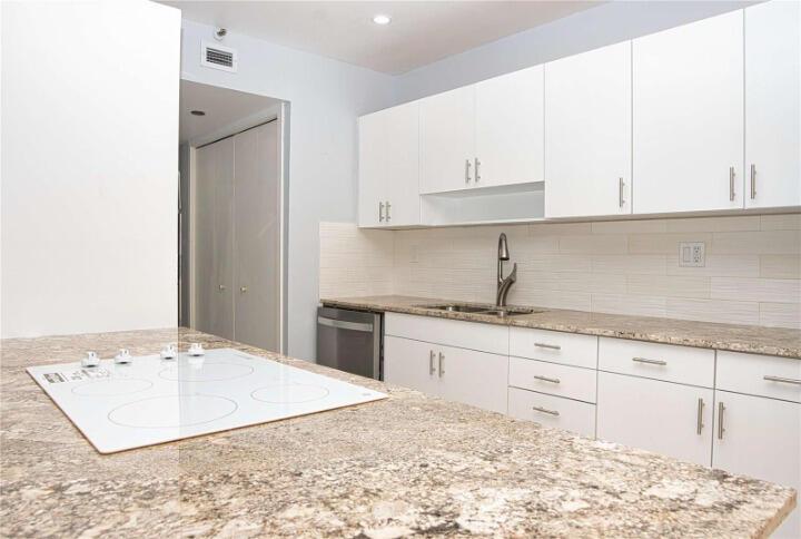 A kitchen features white cabinets, granite countertops, a built-in cooktop, and a stainless steel dishwasher — 19355 Turnberry Way # 3d, Miami FL 33180, MIAMI, FL