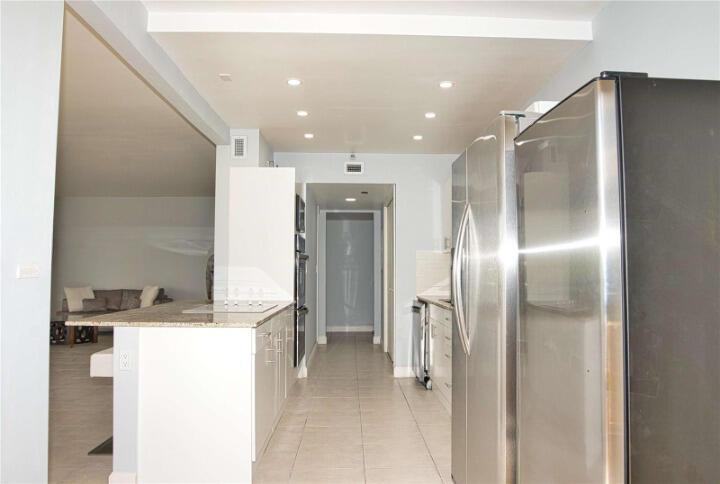 A kitchen with stainless steel appliances, white cabinetry, and a granite-topped island — 19355 Turnberry Way # 3d, Miami FL 33180, MIAMI, FL