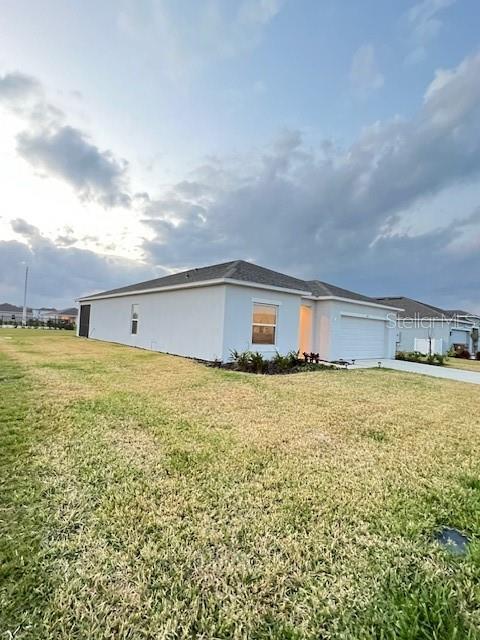 A side view of a single-story house with a white exterior and a garage — 200 AQUAMARINE LANE, KISSIMMEE, FL