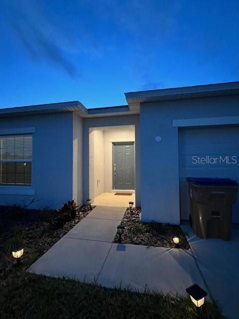 A single-story house exterior features a blue front door, concrete walkway, and a trash bin — 200 AQUAMARINE LANE, KISSIMMEE, FL