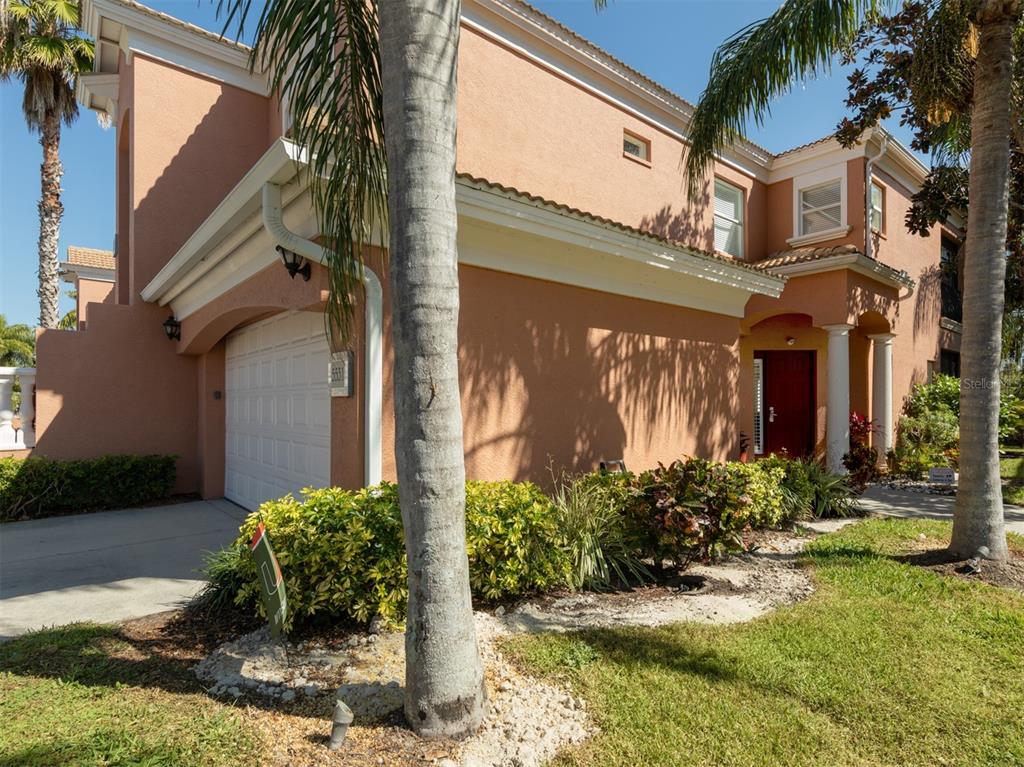 A two-story peach-colored house features a white garage door, a red front door, and palm trees — 5531 46TH COURT W UNIT 5531, BRADENTON, FL