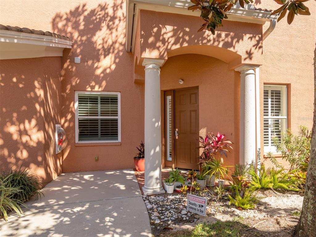 The exterior entrance of a peach-colored home features a covered porch with two white columns — 5531 46TH COURT W UNIT 5531, BRADENTON, FL
