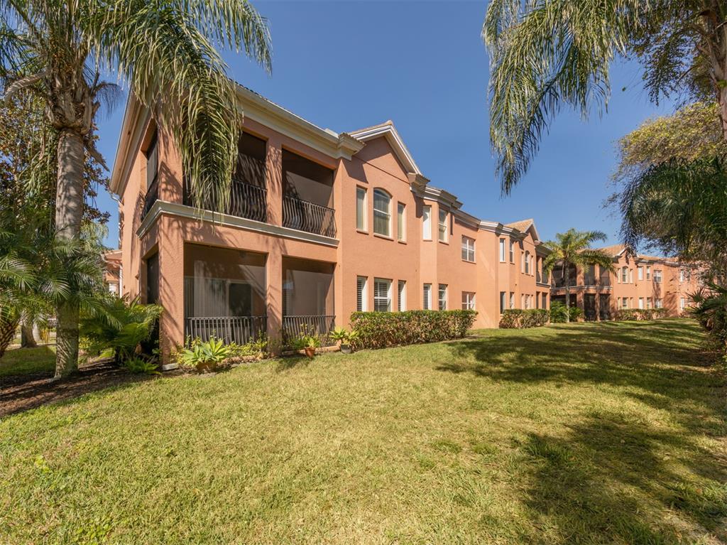 A multi-story peach-colored apartment building with screened balconies and palm trees on a lawn — 5531 46TH COURT W UNIT 5531, BRADENTON, FL