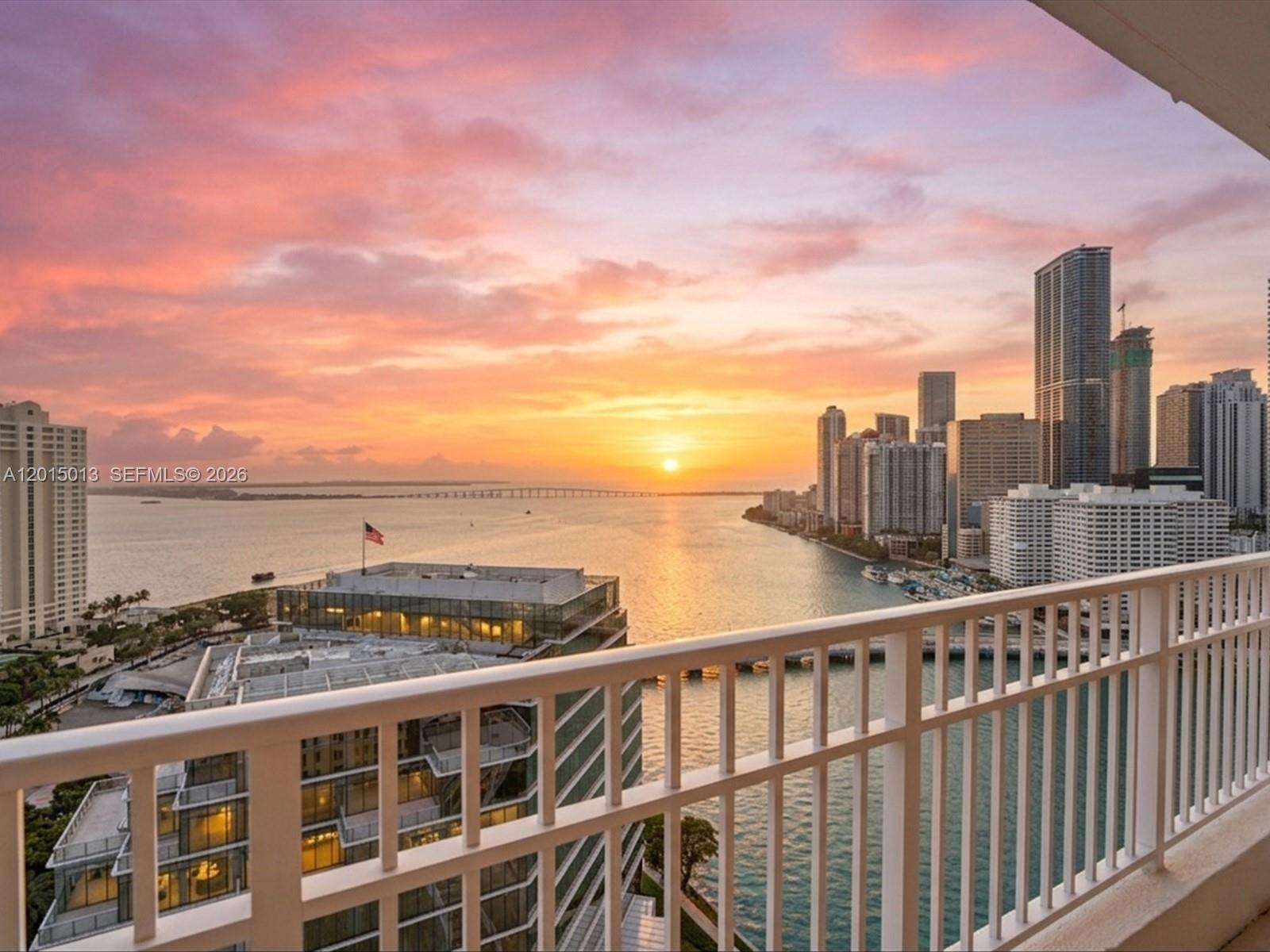A balcony view overlooking a bay, city skyline, and sunset with a white railing — 701 Brickell Key Blvd # 2511, Miami FL 33131, MIAMI, FL