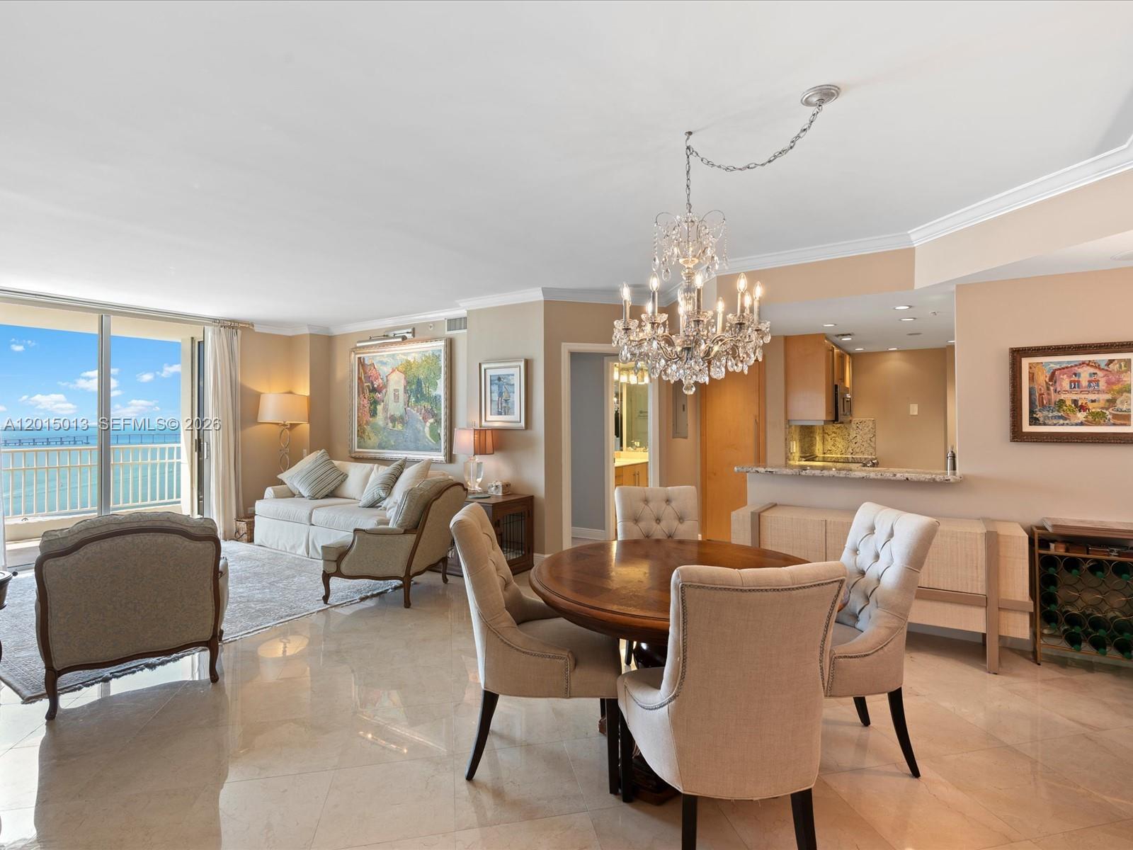 An open-concept living and dining area features tile floors, a crystal chandelier, and ocean views — 701 Brickell Key Blvd # 2511, Miami FL 33131, MIAMI, FL