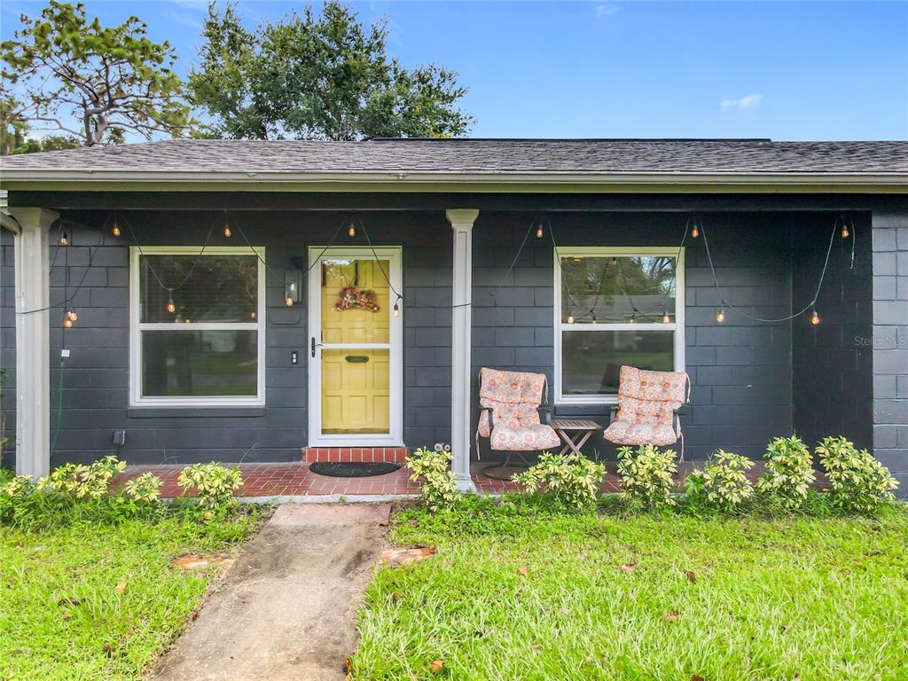 A dark gray house exterior features a yellow front door, string lights, and a porch — 1098 HENRY BALCH DRIVE, ORLANDO, FL