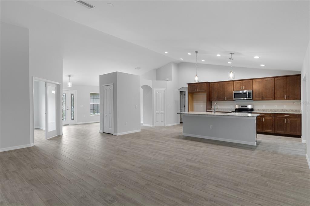 An open-concept kitchen and living area featuring wood-toned cabinets, a center island, and tile flooring — 4118 N PINK POPPY DRIVE, BEVERLY HILLS, FL