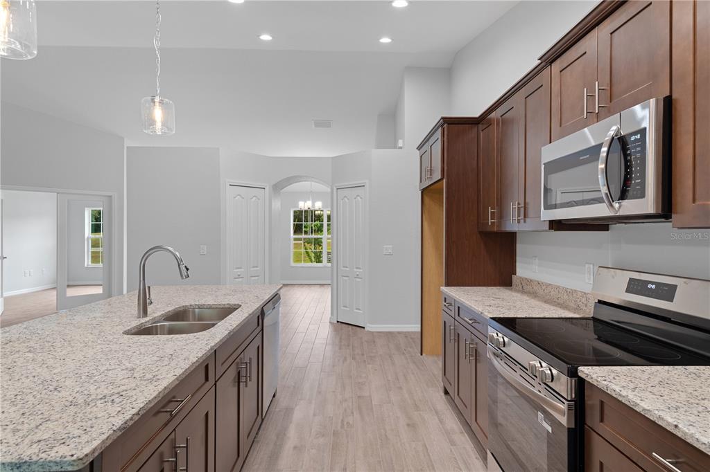 A kitchen with dark wood cabinets, granite countertops, a center island, and stainless steel appliances — 4118 N PINK POPPY DRIVE, BEVERLY HILLS, FL