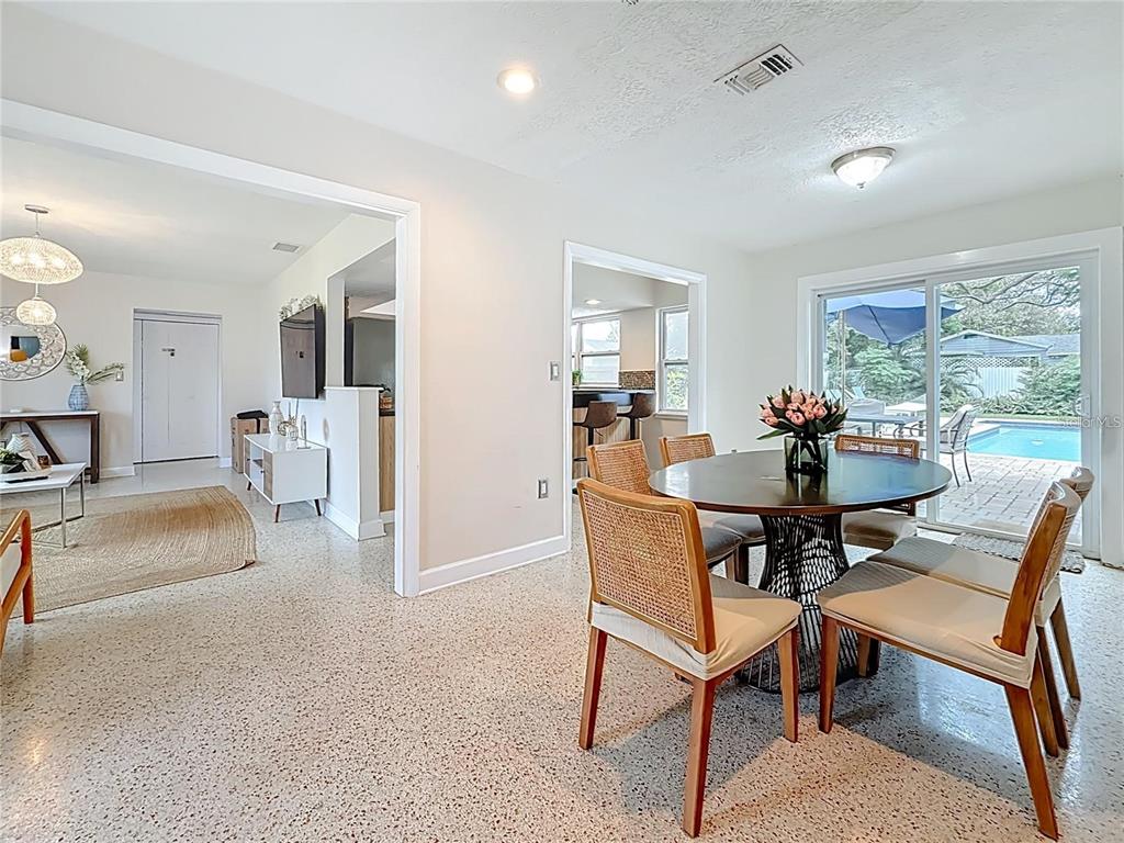 A dining area with a round table and rattan chairs overlooks a backyard swimming pool — 14626 WILDWOOD DRIVE, LARGO, FL