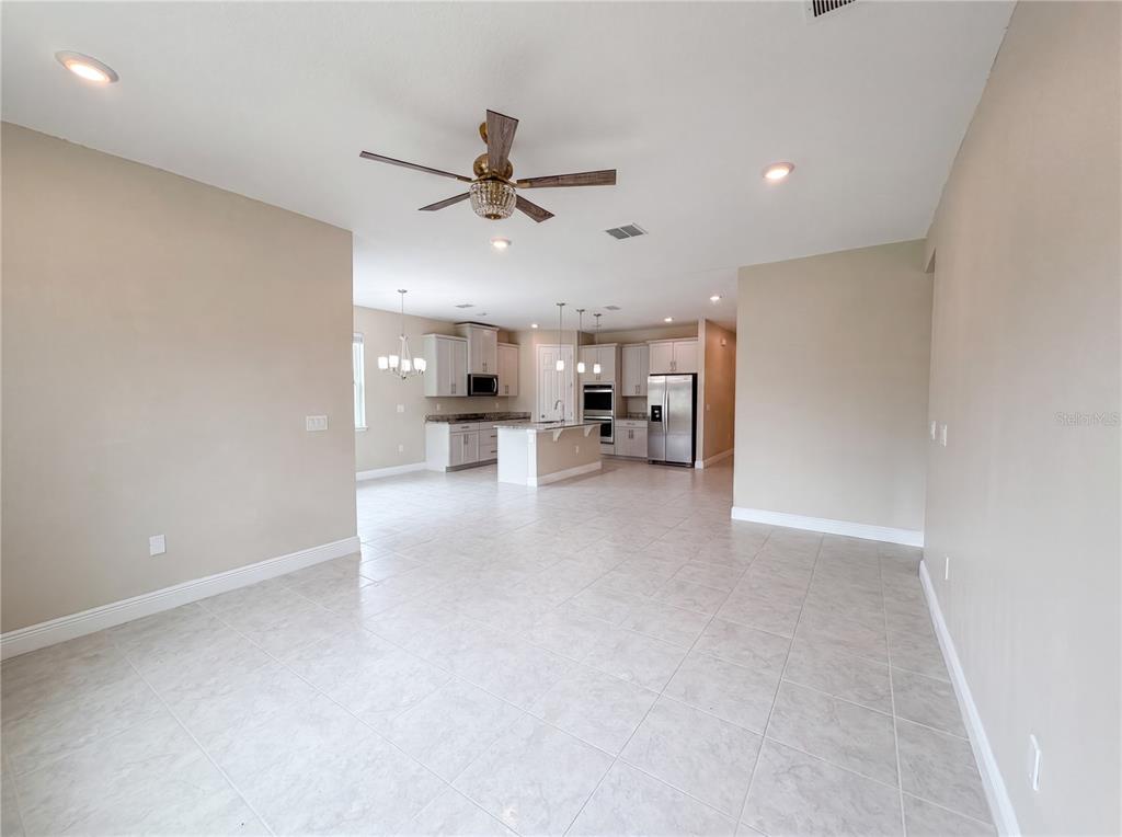 An open-concept kitchen features light-colored cabinetry, a central island, and tile flooring — 528 BELLISSIMO PLACE, HOWEY IN THE HILLS, FL