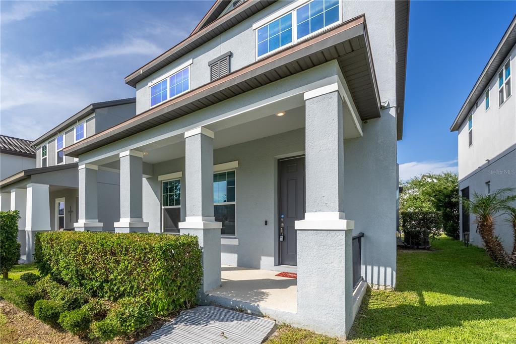 A gray two-story house features a covered front porch with square columns and landscaping — 2247 WHITE FEATHER LOOP, OAKLAND, FL