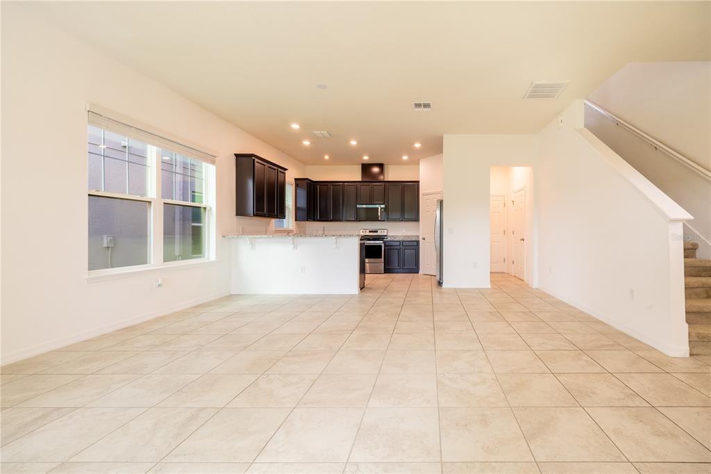 An open-concept kitchen features dark wood cabinets, granite countertops, and tile flooring — 2247 WHITE FEATHER LOOP, OAKLAND, FL