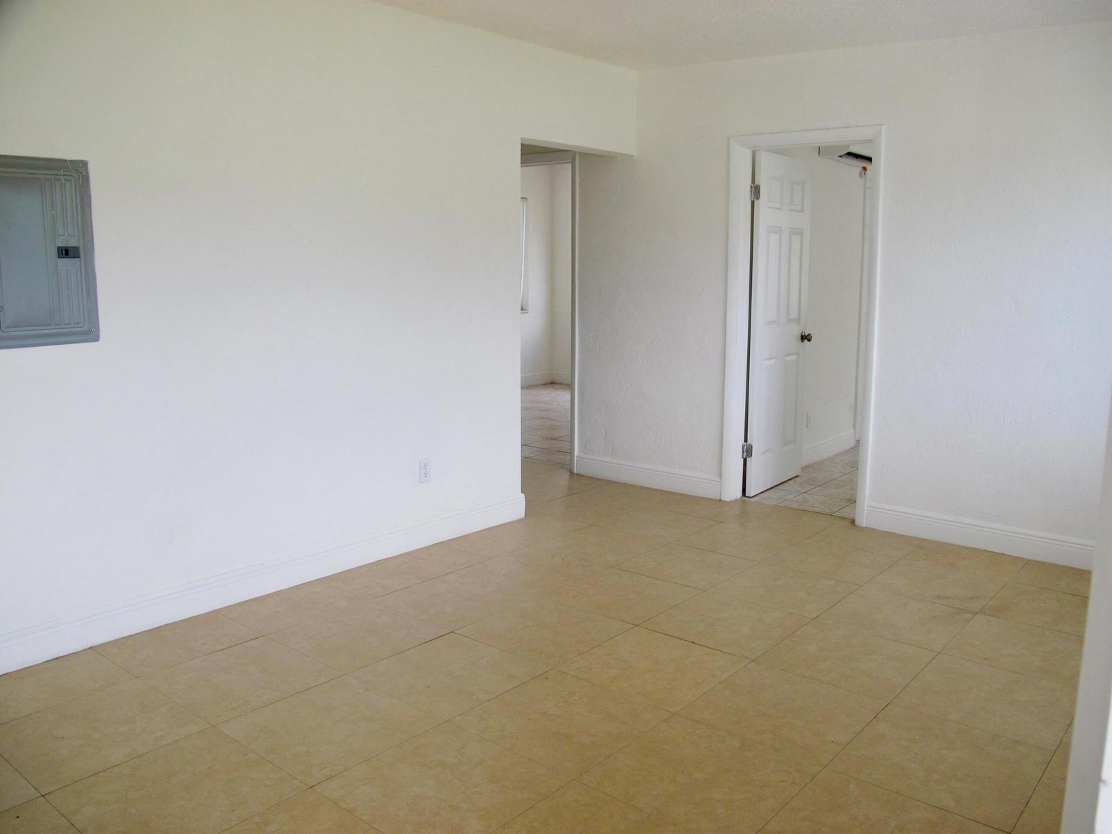 An empty room with white walls, beige tile flooring, a circuit breaker panel, and two doorways — 340 NW 6th Street # 2, Pompano Beach FL 33060, POMPANO BEACH, FL