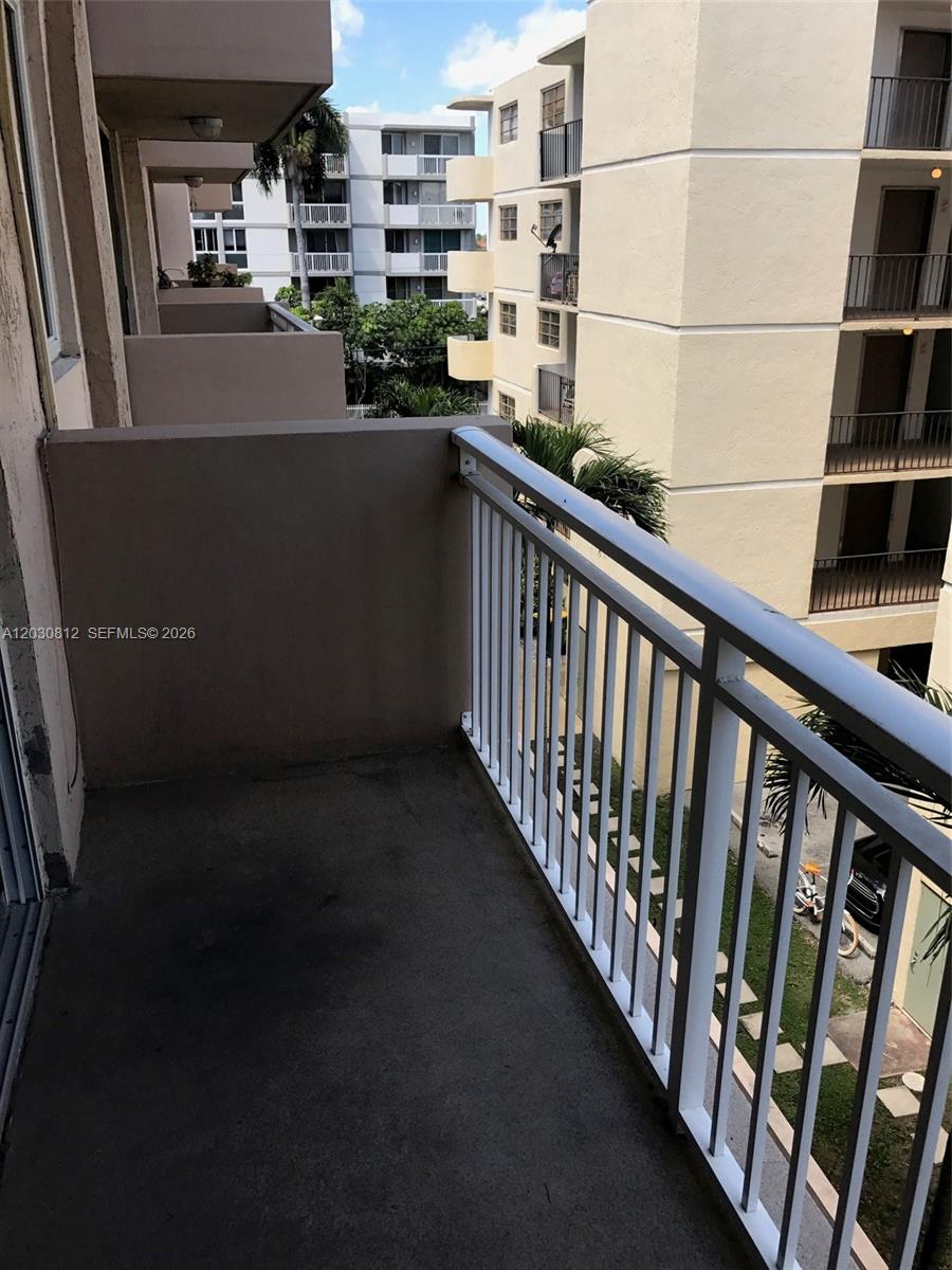 A concrete balcony with a white metal railing overlooks a neighboring apartment building — 1665 Bay Rd # 416, Miami Beach FL 33139, MIAMI BEACH, FL