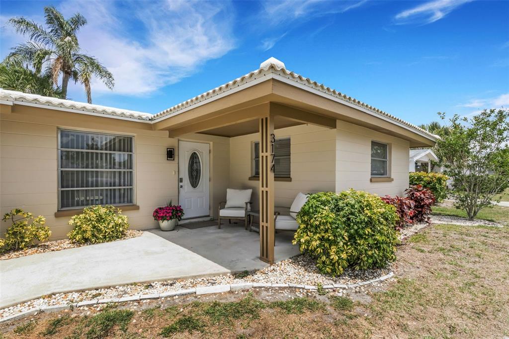 The exterior of a single-story house features a covered front porch and a concrete walkway — 3174 REGATTA CIRCLE, SARASOTA, FL