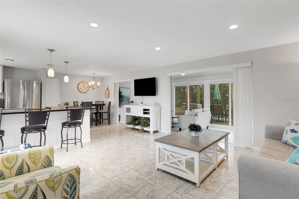 An open-concept living and dining area features tile flooring, a kitchen island, and sliding doors — 3174 REGATTA CIRCLE, SARASOTA, FL