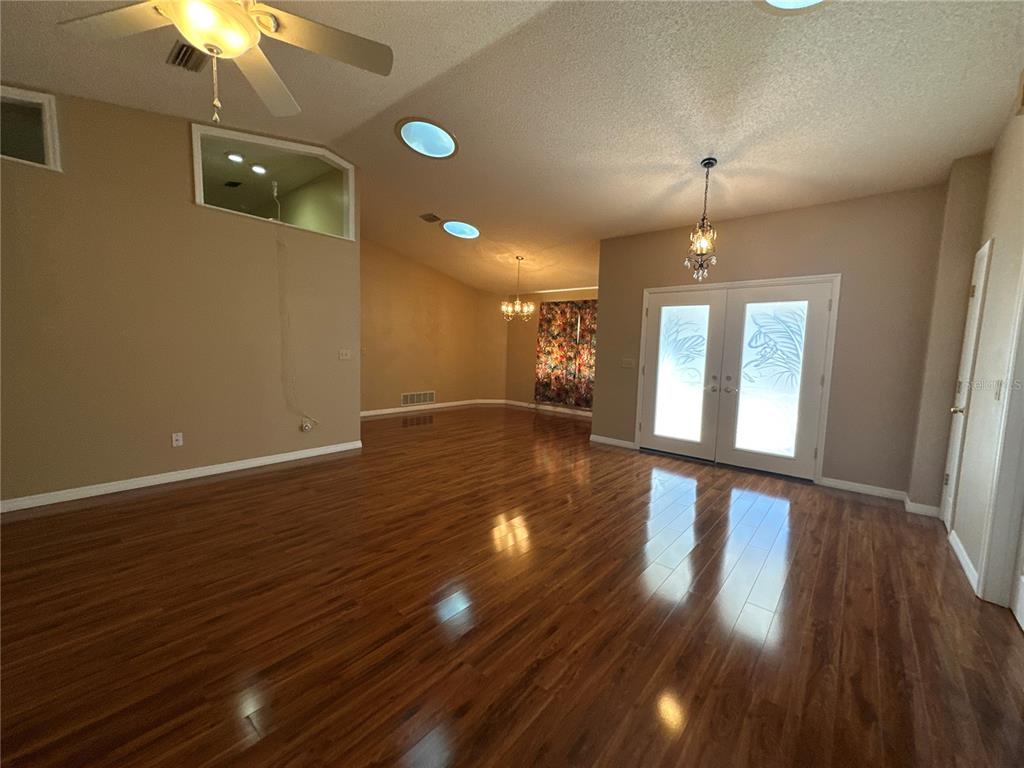 A spacious living area features hardwood flooring, a ceiling fan, and double glass-paneled doors — 100 WEBSTER LANE, PALM COAST, FL