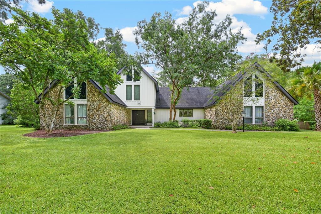 A two-story house with stone siding, a dark roof, and a large front lawn — 5360 NE 1ST LANE, OCALA, FL