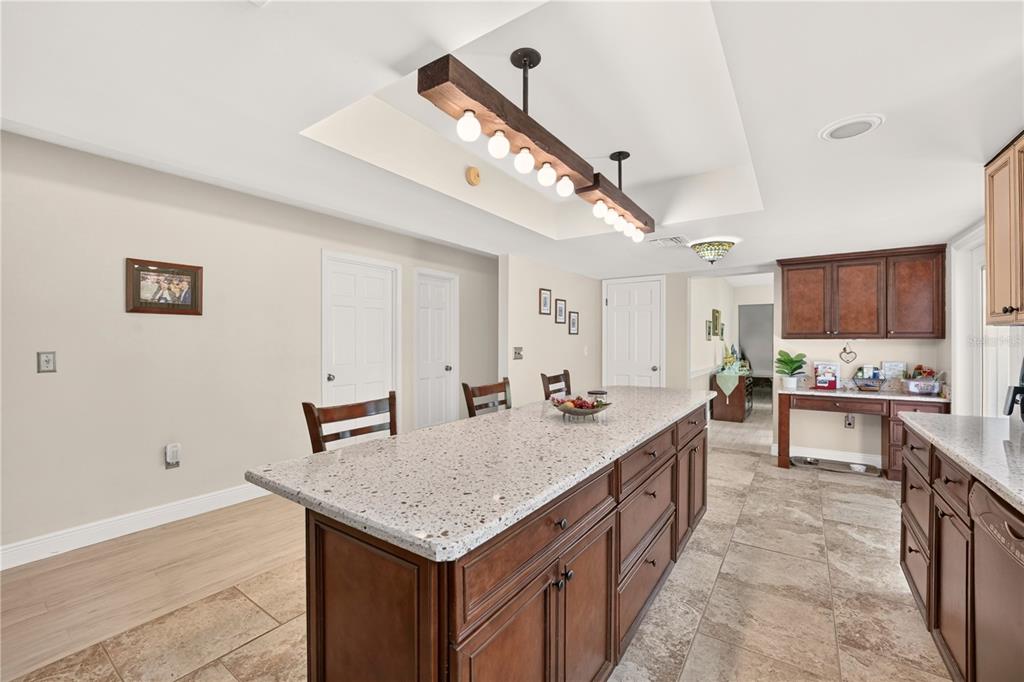 A kitchen features a large granite-topped island, dark wood cabinetry, and a rustic pendant light — 5360 NE 1ST LANE, OCALA, FL