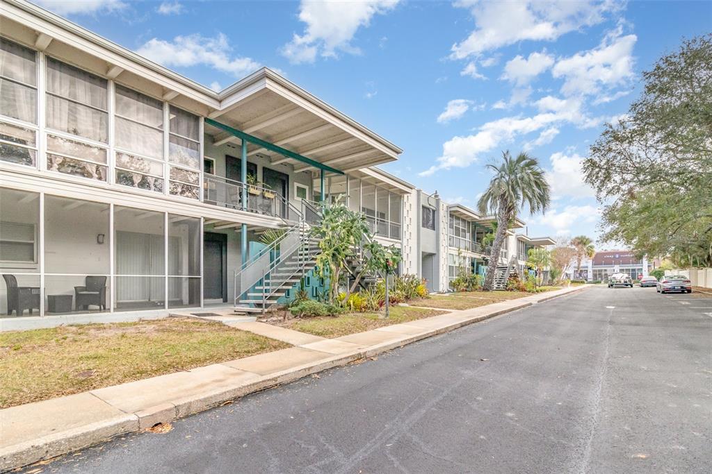 A two-story apartment building with screened-in porches and an exterior staircase sits beside a street — 151 N ORLANDO AVENUE UNIT 207, WINTER PARK, FL