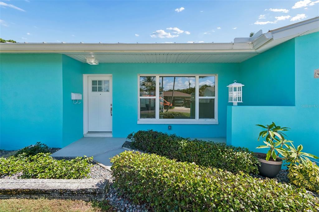 A bright turquoise house exterior features a white front door and a large window — 4388 50TH PLACE S, ST PETERSBURG, FL
