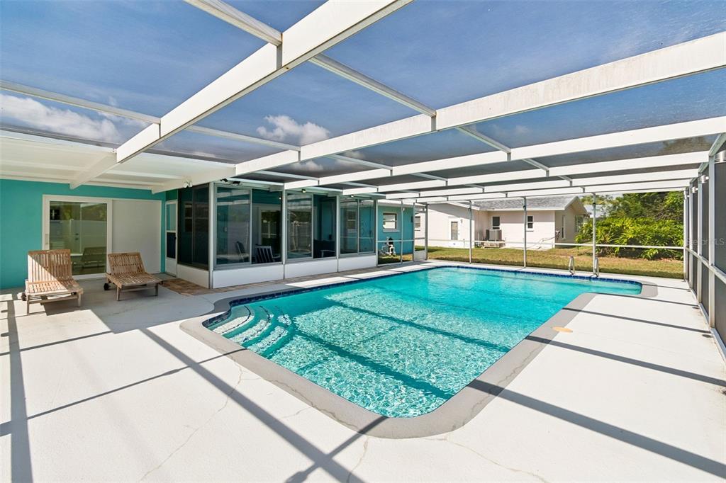 A swimming pool sits on a concrete patio enclosed by a white screen cage — 4388 50TH PLACE S, ST PETERSBURG, FL