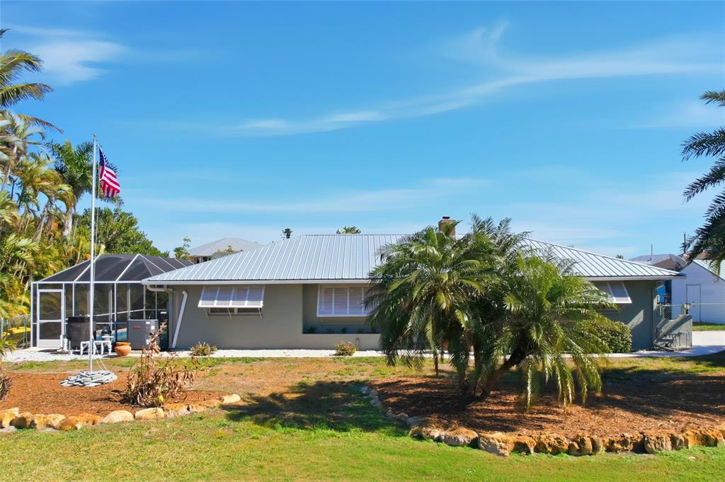 A single-story house with a metal roof, a screened pool enclosure, and a flag pole — 2740 SANIBEL BOULEVARD, ST JAMES CITY, FL