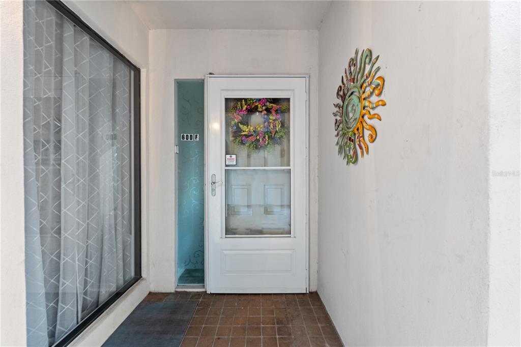 A white front door with a wreath and a sun wall decoration on a porch — 300 S FLORIDA AVENUE UNIT 600F, TARPON SPRINGS, FL
