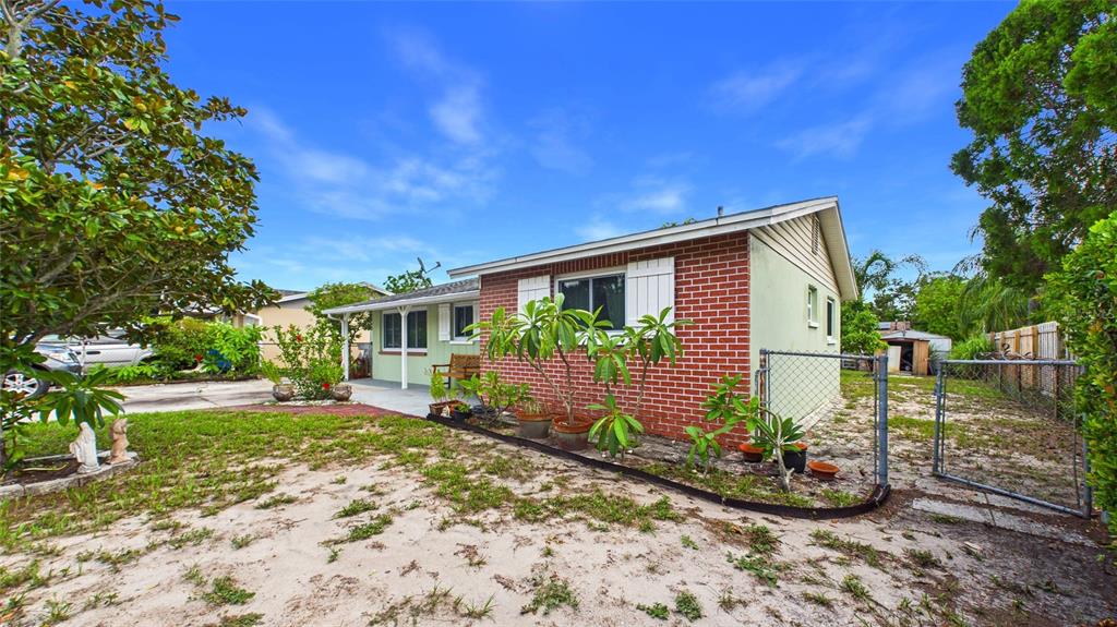 A single-story brick house with a fenced yard and potted plants in the front — 2809 EDENWOOD STREET, CLEARWATER, FL