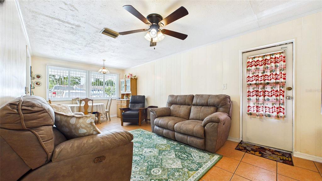 A living room with tile floors, a ceiling fan, brown furniture, and a dining area — 2809 EDENWOOD STREET, CLEARWATER, FL