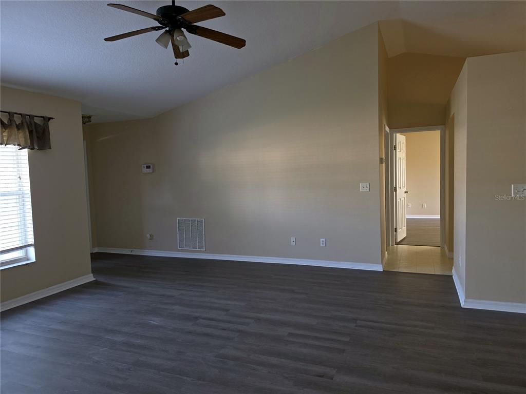 A living room with vaulted ceilings, dark wood-look flooring, and a ceiling fan — 1750 NE 40TH STREET, OCALA, FL