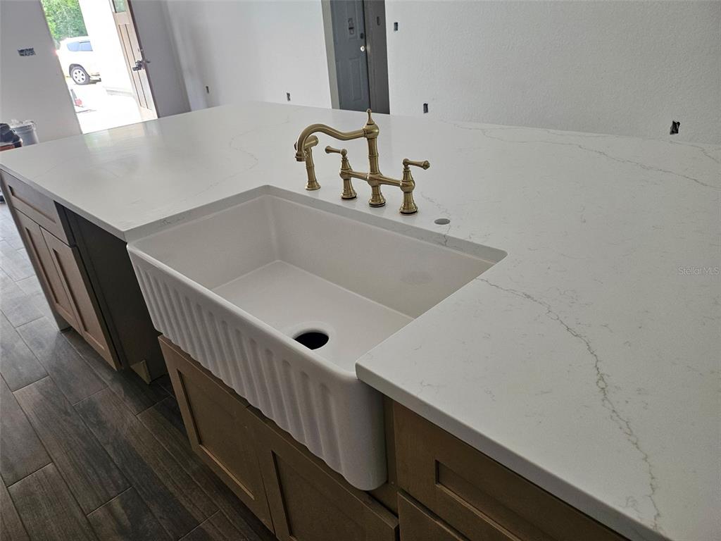 A kitchen island features a white farmhouse sink, brass faucet, and white quartz countertops — 7 FIR DRIVE TRACK, OCALA, FL