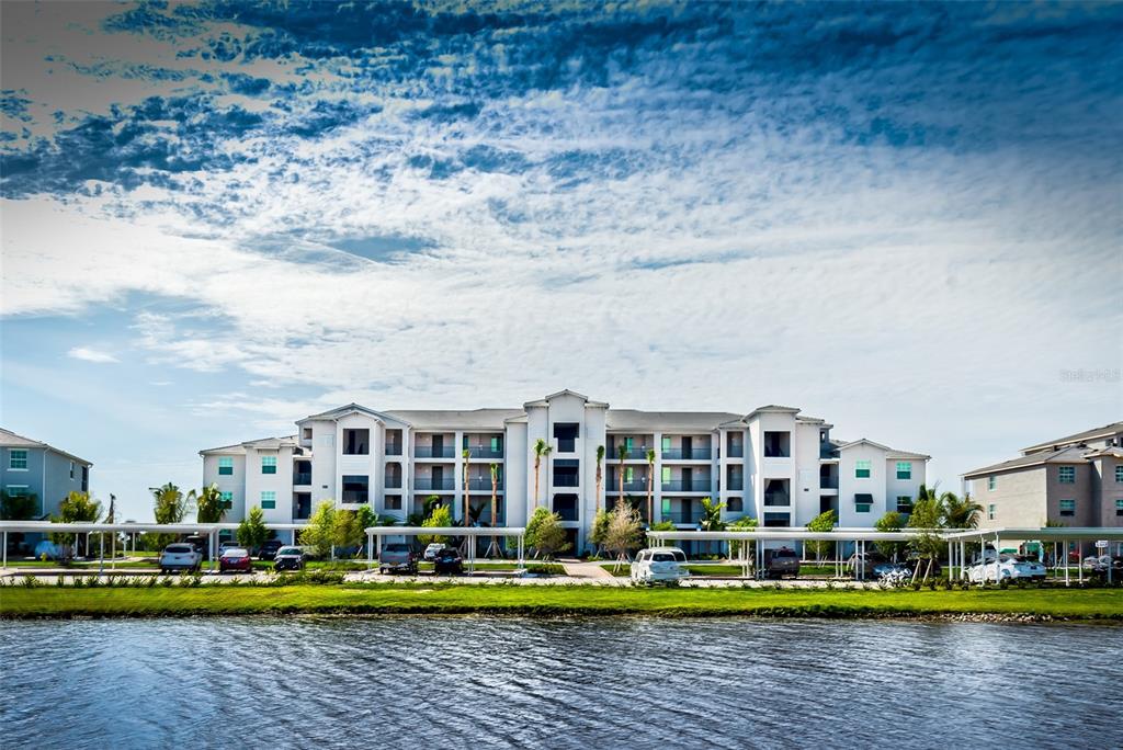 A multi-story apartment building sits behind a parking lot and a body of water — 14061 HERITAGE LANDING BOULEVARD UNIT 411, PUNTA GORDA, FL