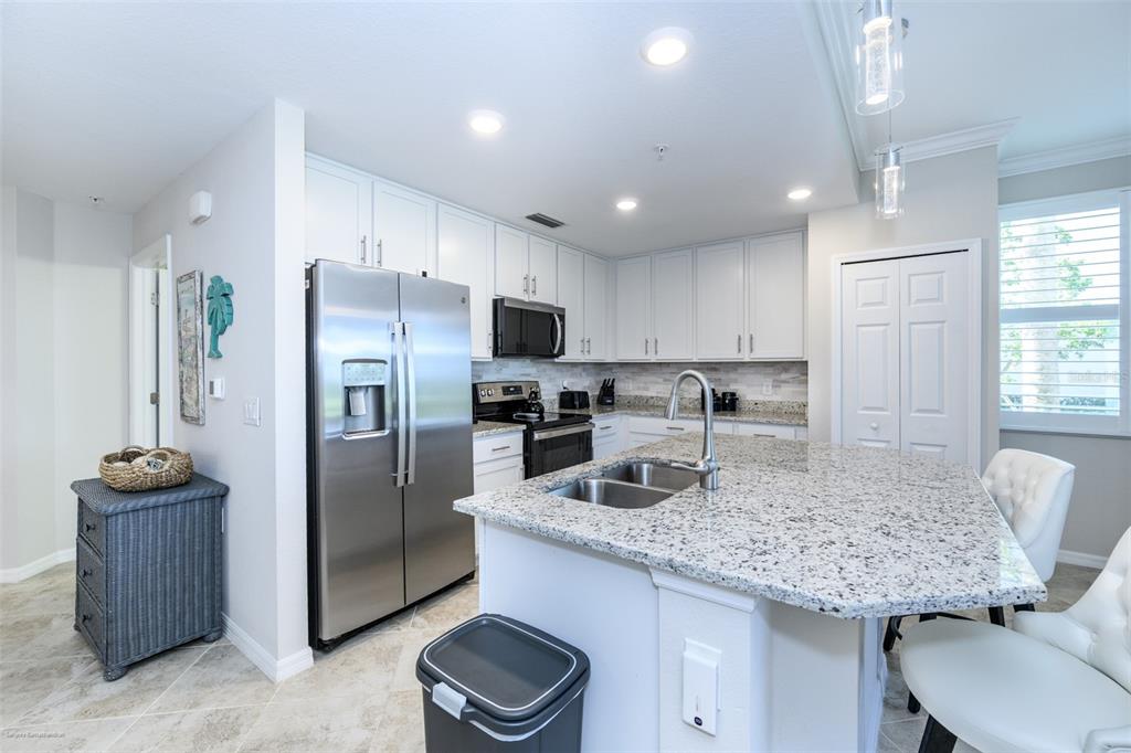 A kitchen features white cabinetry, granite countertops, stainless steel appliances, and a central island — 14061 HERITAGE LANDING BOULEVARD UNIT 411, PUNTA GORDA, FL