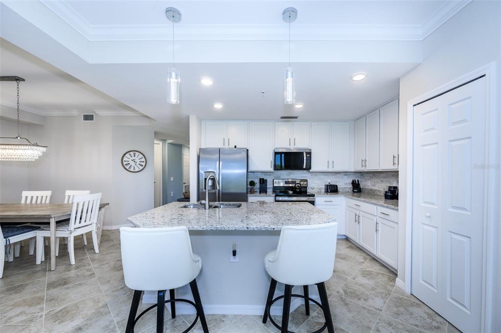 A kitchen features white cabinets, granite countertops, a center island, and a dining area — 14061 HERITAGE LANDING BOULEVARD UNIT 411, PUNTA GORDA, FL