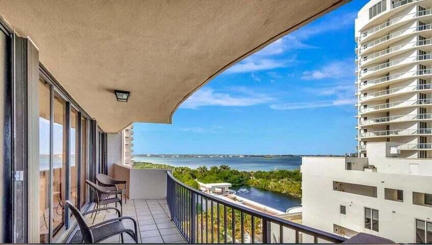 A balcony with patio furniture overlooks a body of water and a nearby high-rise building — 4200 N Ocean Drive # 905, Riviera Beach FL 33404, RIVIERA BEACH, FL