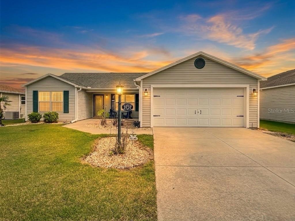 A single-story house with light gray siding, a two-car garage, and a concrete driveway — 3737 COSMOS WAY, THE VILLAGES, FL