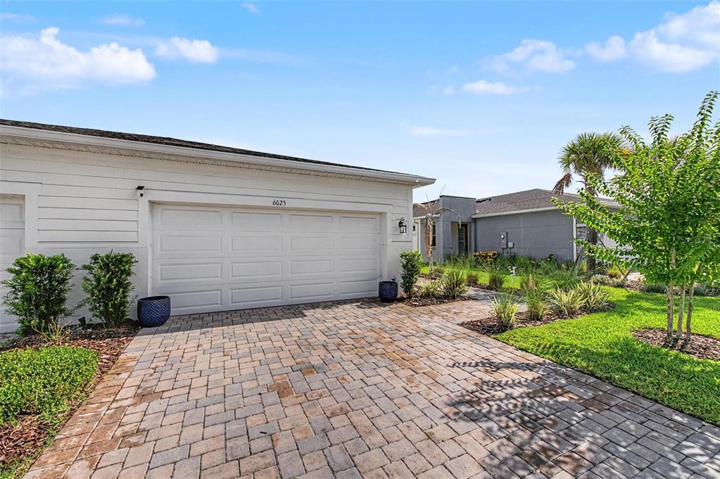 A white house with a two-car garage and a paved driveway under a blue sky — 6025 TIMBERDALE AVENUE, WESLEY CHAPEL, FL