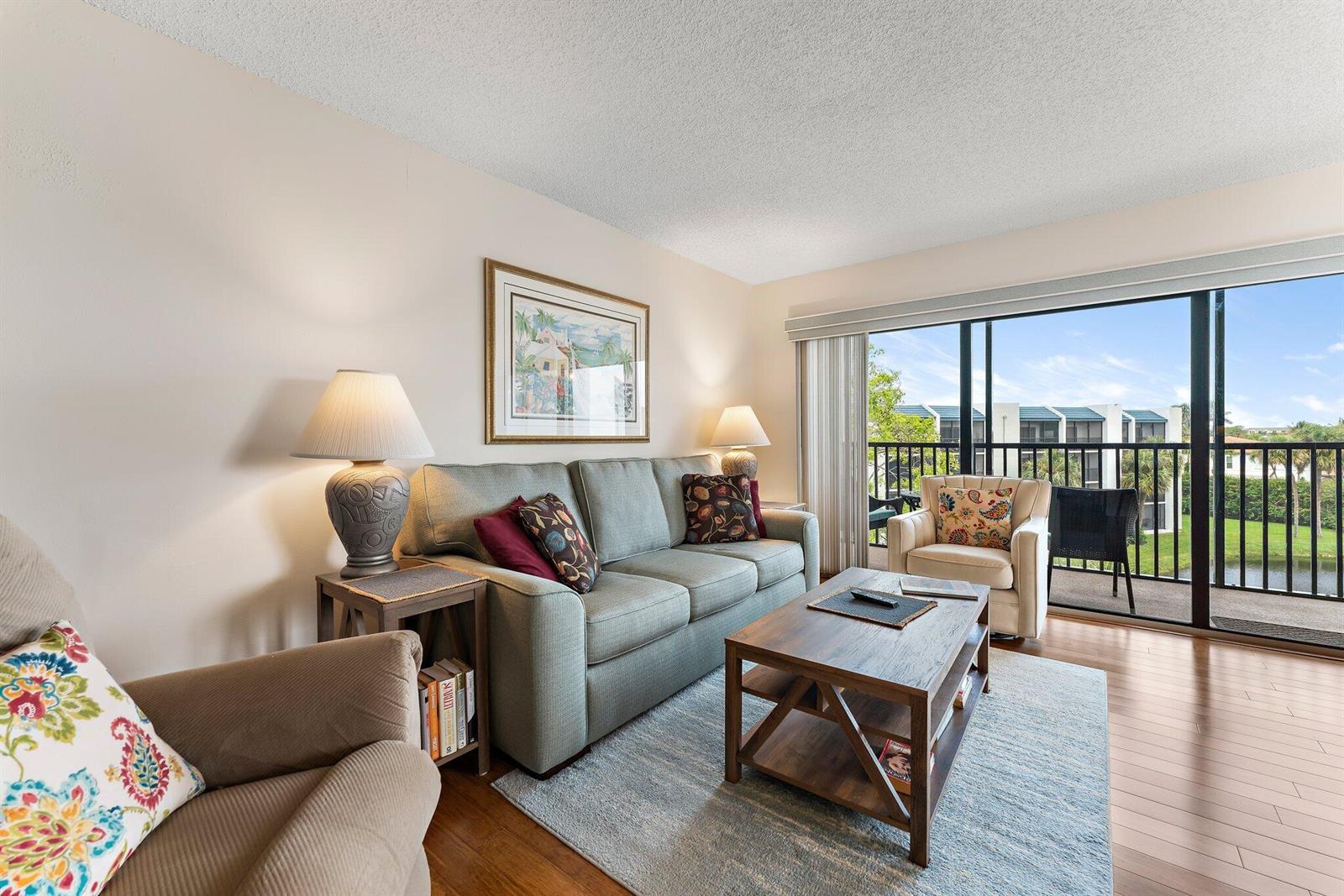 A living room features a sofa, armchairs, a coffee table, and a balcony with outdoor seating — 1605 S Us Highway 1 # B406, Jupiter FL 33477, JUPITER, FL