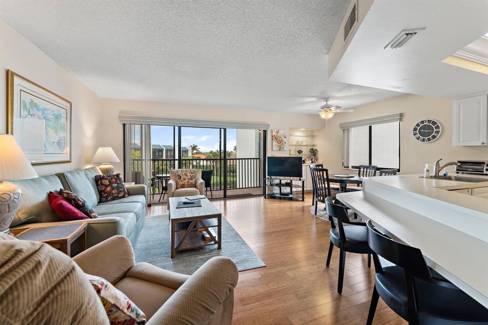 A living room and dining area with hardwood floors, a balcony, and a breakfast bar — 1605 S Us Highway 1 # B406, Jupiter FL 33477, JUPITER, FL